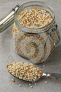 Glass jar and a spoon with raw uncooked pearl couscous