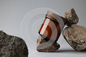 Glass jar and stones on grey background, closeup