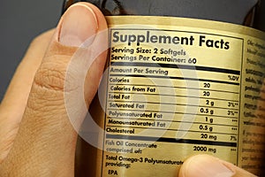 Glass jar with supplement facts in woman hands.