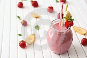 Glass jar with tasty strawberry smoothie on wooden table