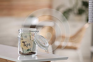 Glass jar with tips on table indoors. Space for text