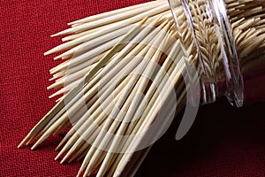 GLASS JAR WITH TOOTH PICKS TIPPED OVER ON A RED CLOTH