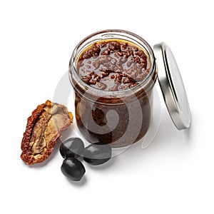 Glass jar with traditional homemade black olive tapenade close up on white background photo