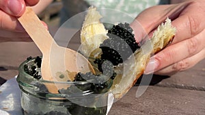 with a glass jar a wooden spoon scoop black caviar on a bun on a croissant tasting tasting delicious food caviar fish