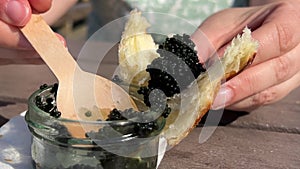 With a glass jar a wooden spoon scoop black caviar on a bun on a croissant tasting tasting delicious food caviar fish