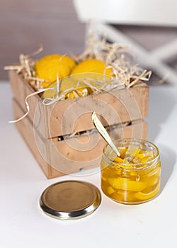 Glass jar with yuzu jam near a wooden box with citrus yuzu fruit. yuja-cheong is marmalade made from yuzu zest, juice and honey photo