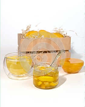 Glass jar with yuzu jam near a wooden box with citrus yuzu fruit. yuja-cheong is marmalade made from yuzu zest, juice and honey photo