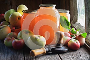 Glass jars of apple juice, apples and can lid closing machine for canning.