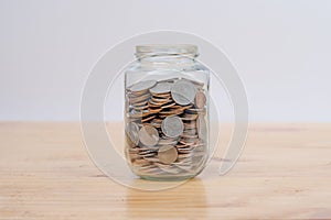 Glass jars with coins on wooden desk. Savings and Investments concept