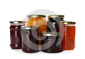 Glass jars with different pickled fruits and jams on background