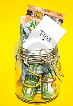 Glass jars filled with Euro bills, savings inside glass jar, money isolated on yellow background. Paper note written