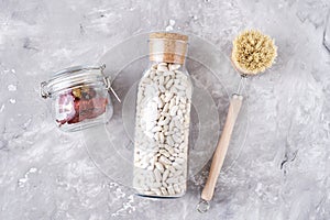 Glass jars with food ingredients on a gray background, top view. Zero waste concept. Kitchen background with eco friendly utensils