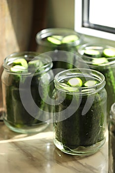 Glass jars with fresh cucumbers on table, closeup. Canning vegetables
