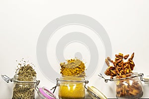 glass jars full of spices upended on a smooth white surface