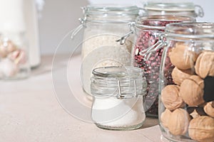 glass jars with grains, nuts and sugar on a kitchen table. sustainable home grocery storage and zero plastic house. eco