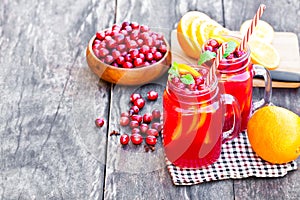 Glass jars of homemade juice with orange slices and wild cranberry