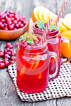 Glass jars of homemade juice with orange slices and wild cranberry