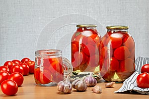 Glass jars with homemade pickled tomatoes, sealed with fresh tomato