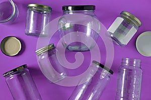 Glass jars with lids, purple background, top view flat lay recycling concept