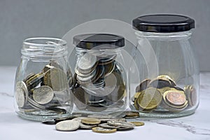 Glass jars with multicurrency coins on a table