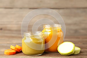 Glass jars with nutrient baby food on grey wooden background