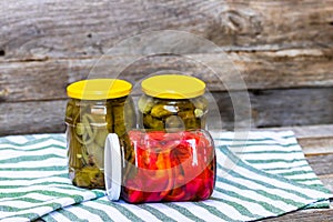 Glass jars with pickled red bell peppers and pickled cucumbers pickles isolated. Jars with variety of pickled vegetables.