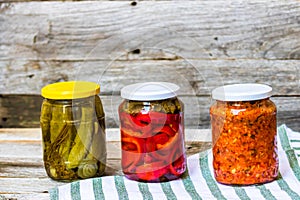 Glass jars with pickled red bell peppers and pickled cucumbers pickles isolated. Jars with variety of pickled vegetables.