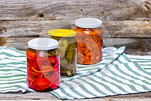 Glass jars with pickled red bell peppers and pickled cucumbers pickles isolated. Jars with variety of pickled vegetables.