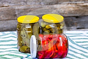 Glass jars with pickled red bell peppers and pickled cucumbers pickles isolated. Jars with variety of pickled vegetables.