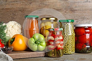 Glass jars with pickled vegetables on wooden table