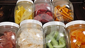 Glass jars with various dried fruits on a wooden background in a food store.