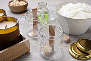 Glass jars with wicks and flowers on light wooden table. Making homemade candles