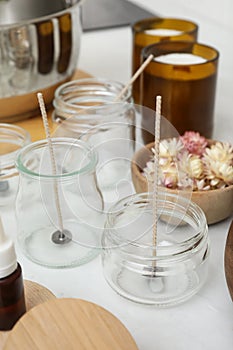 Glass jars with wicks on white kitchen table. Making homemade candles