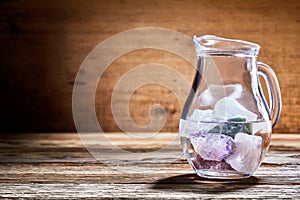 Glass jug with assorted healing stones in water