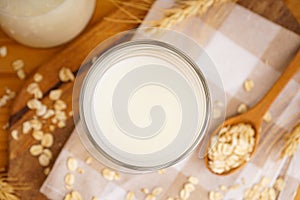 Glass and jug of fresh milk on wooden table against color background. Top view