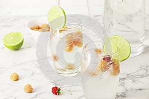 Glass and jug with fresh water and lime on marble table. Space for text. Flavored water. Summer drinks.