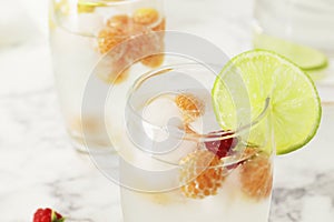 Glass and jug with fresh water and lime on marble table. Space for text. Flavored water. Summer drinks.