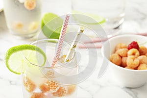 Glass and jug with fresh water and lime on marble table. Space for text. Flavored water. Summer drinks