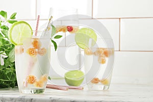 Glass and jug with fresh water and lime on marble table. Space for text. Flavored water. Summer drinks