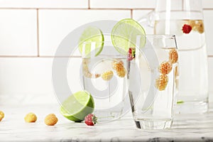 Glass and jug with fresh water and lime on marble table. Space for text. Flavored water. Summer drinks.