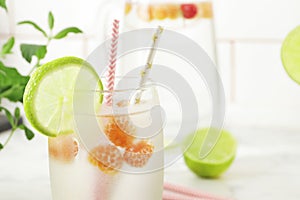 Glass and jug with fresh water and lime on marble table. Space for text. Flavored water. Summer drinks.