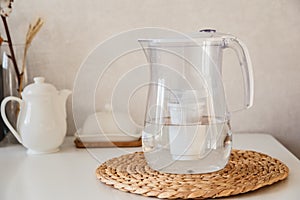 Glass and jug with fresh water on table in the kintchen