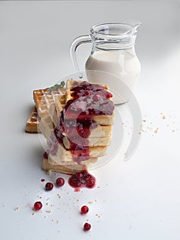 A glass jug with milk next to a square bowl with cereals