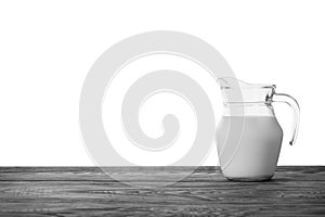 Glass jug of milk on wooden table