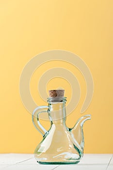 A glass jug with a natural cork on a white-and-yellow background
