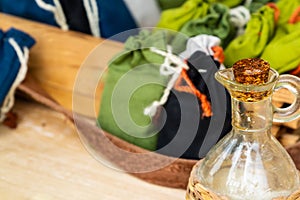 Glass jug with olive oil closed wooden cork, aromatherapy traditional medicine stands blurry background sachet herb sack