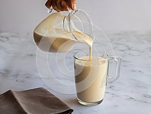 A glass jug and pours fermented baked milk in a glasse