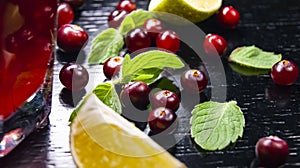 Glass with juice, lime wedge, mint and cranberries