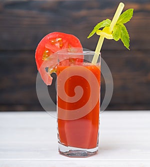 Glass of juice with slice of tomato in close up