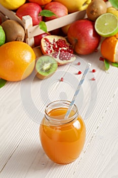 A glass of juice with a straw from different fruits